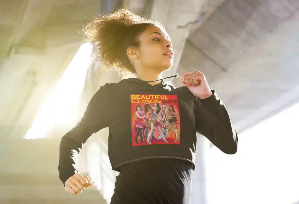 running model wearing black cropped katseye hoodie with beautiful chaos design